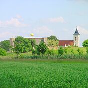 Vollmondskulptur vor Ruine und Kirche